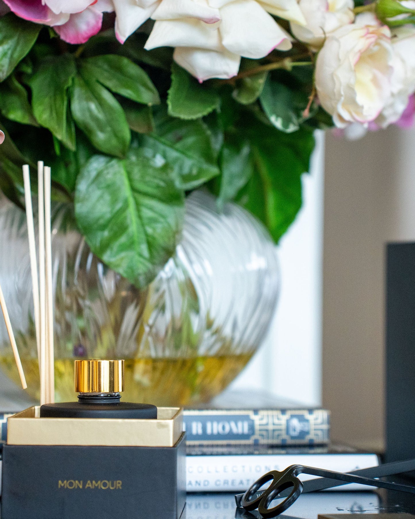 Person using an incense stick with a floral arrangement and product packaging in the background