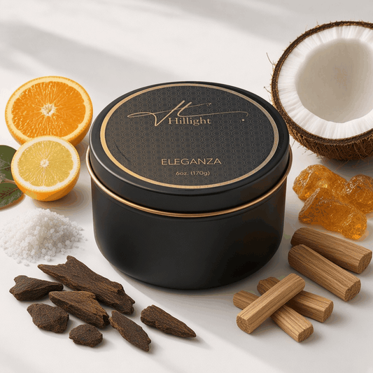 Eleganza Hillight travel candle with matte black lid and gold ring label beside oud wood, citrus and coconut