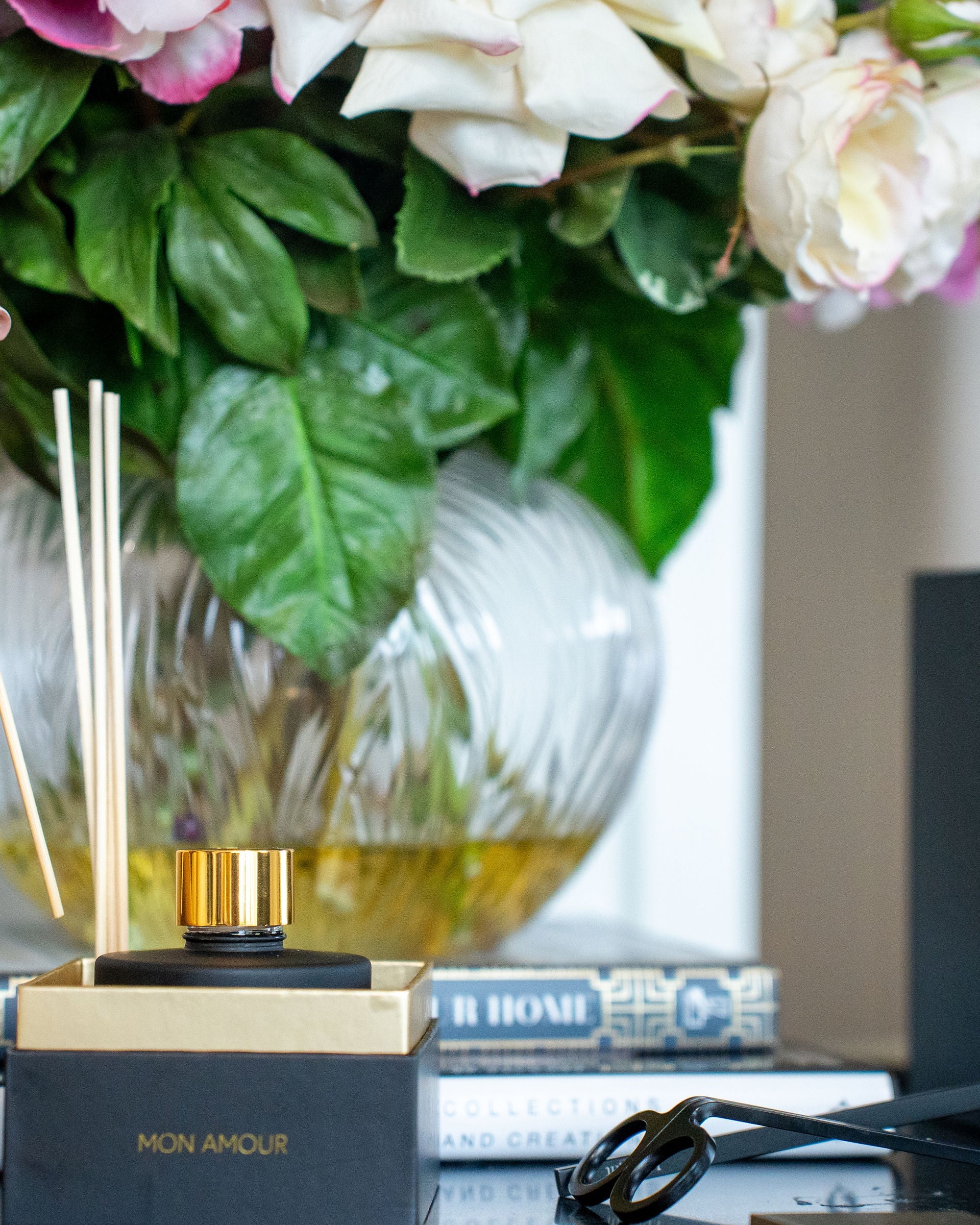Person using an incense stick with a floral arrangement and product packaging in the background